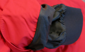 Innenliegender Schneefang aus dunklem, elastischem Stoff am Saum einer roten Winterjacke